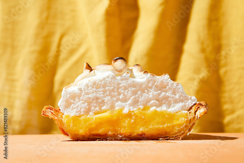 Lemon meringue pie with bright hard light on an orange foreground and yellow backdrop photo