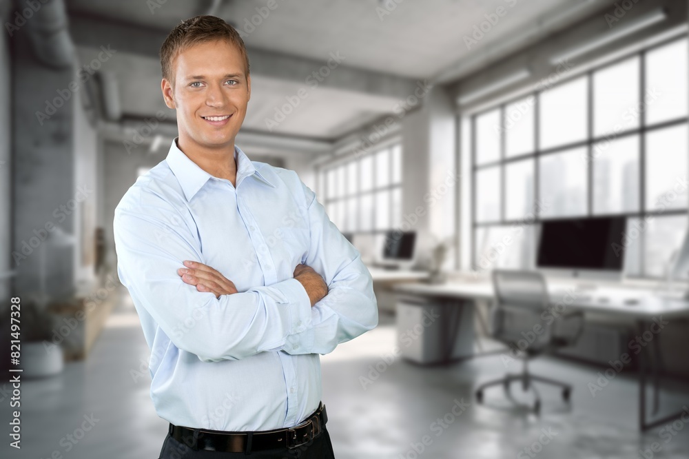 Happy businessman standing at workplace in office Happy businessman standing at workplace in office