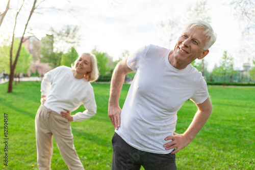 elderly couple of seniors man and woman doing exercises and training in the park outdoors  gray-haired grandparents playing sports and active lifestyle in nature