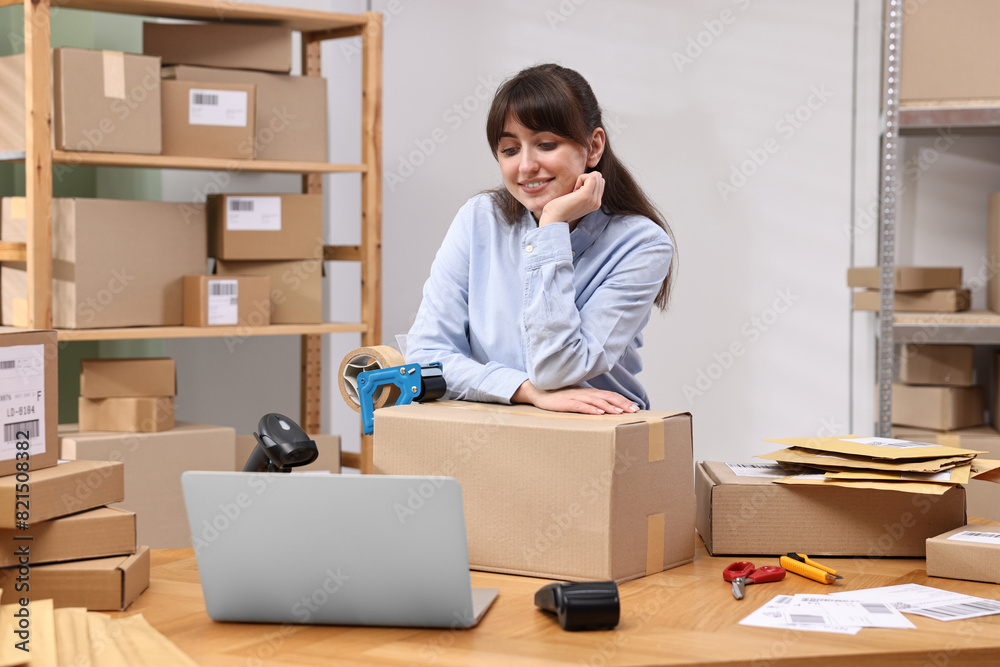 Parcel packing. Post office worker with box at wooden table indoors Parcel packing. Post office worker with box at wooden table indoors