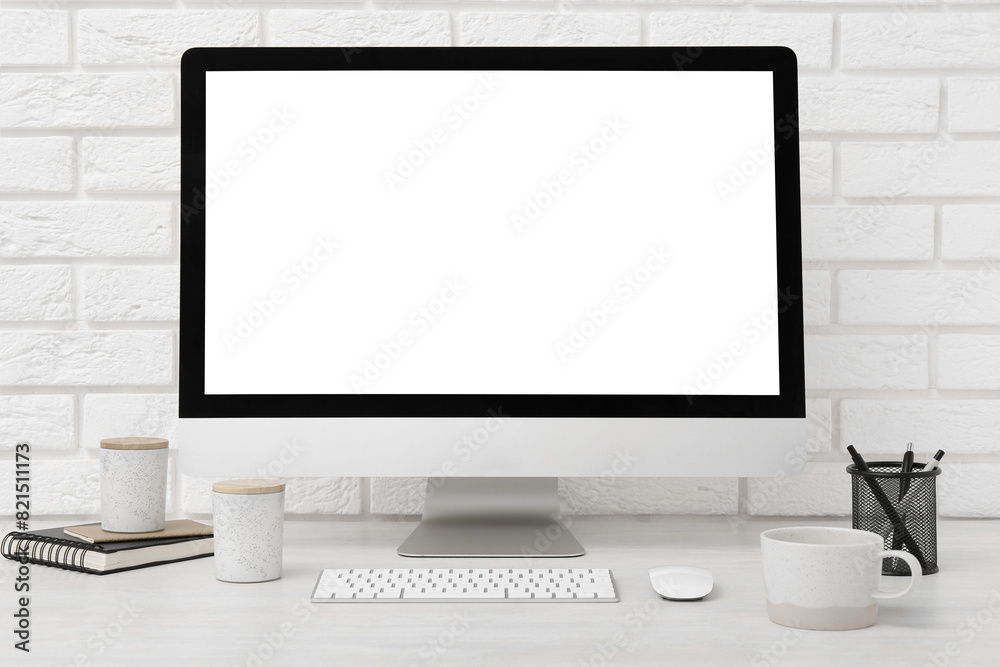 Fototapeta premium Office workplace with computer, cup and stationery on light table near white brick wall