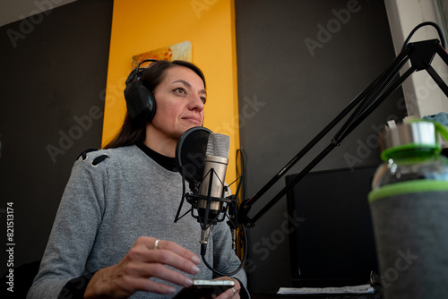 Mujer locutora lista para trabajar en su escritorio, con micrófono y auriculares, tez blanca, cabello negro
