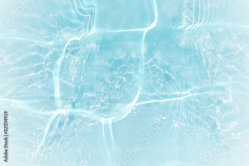 Blue water with ripples on the surface. Defocus blurred transparent blue colored clear calm water surface texture with splashes and bubbles. Water waves with shining pattern texture background