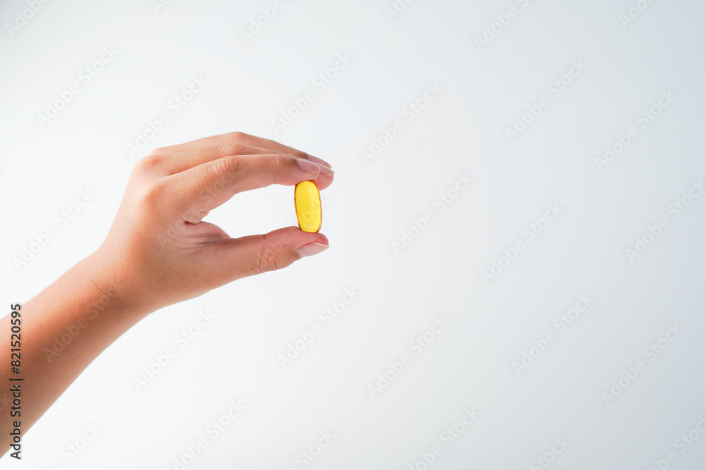 fingers holding a oil filled capsule, soft gel, food supplements, fish oil, omega 3 omega 9 fingers holding a oil filled capsule, soft gel, food supplements, fish oil, omega 3 omega 9