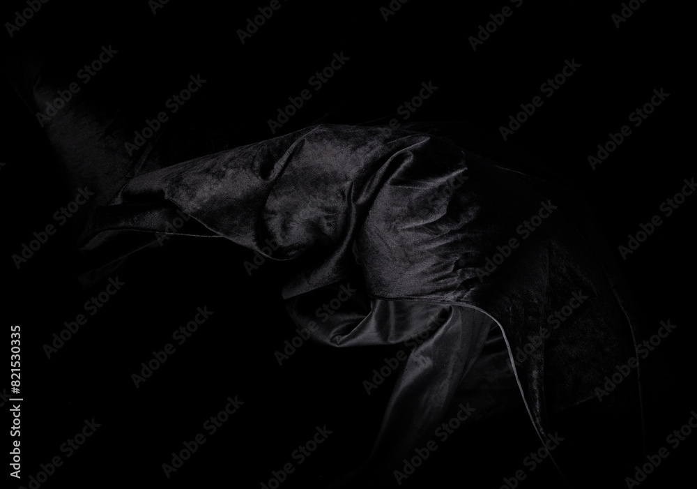 Naklejka premium Black velvet felt fabric flying in curve shape, Piece of textile black velvet felt fabric throw fall in air. Black background isolated, dark shading environment