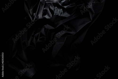 Black wrinkle mussed fabric flying in curve shape, Piece of textile Black wrinkle mussed fabric throw fall in air. Black background isolated, dark shading environment photo