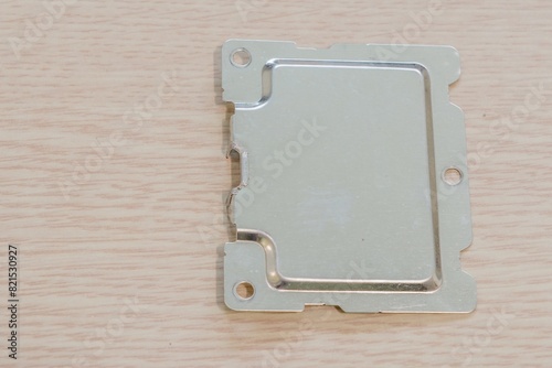 Rectangular metal plate with holes on a light wood background