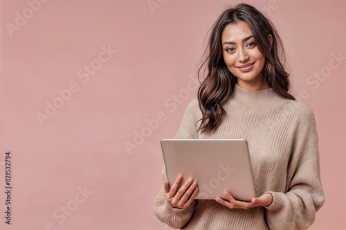A woman holding a tablet or notebook standing against a pink background and isolated. smiling young girl.