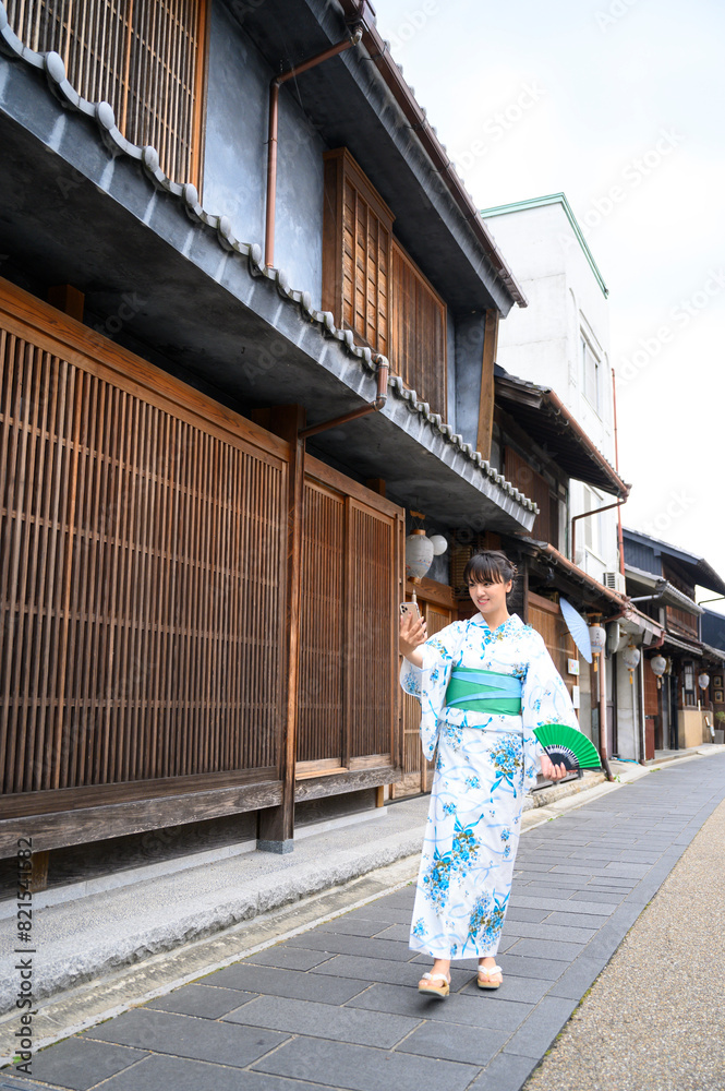 古民家で散歩し写真を撮る浴衣女性