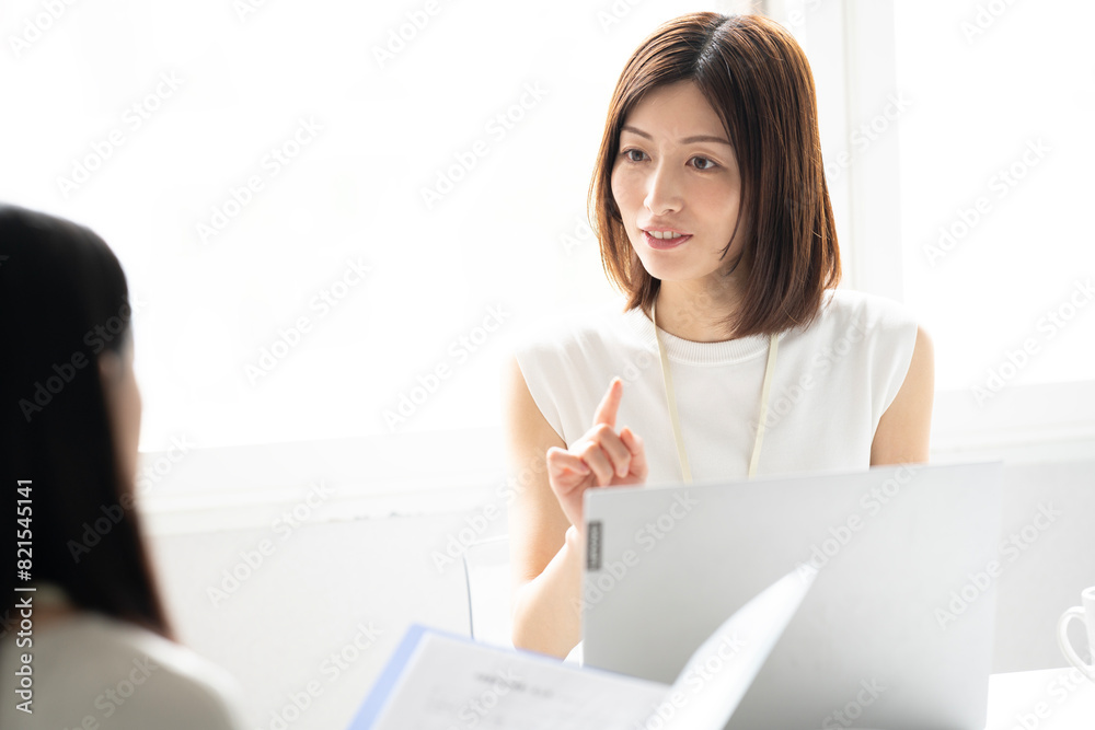 オフィスでパソコンを開いて打ち合わせをしている女性2人