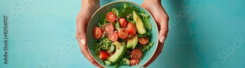 Close up of a woman's hands holding a bowl with fresh vegetables, tomatoes and greens for a salad on a blue background, copy space concept. Vibrant colors, studio lighting, Sony a7 IV, F/4 aperture se photo