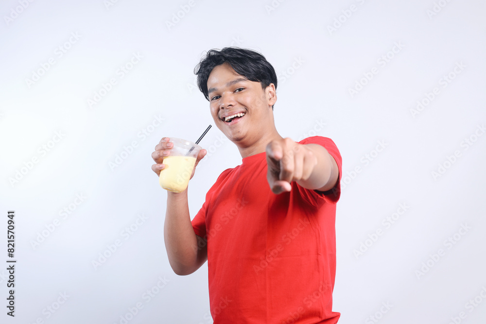 Potrait Of Happy Young Asian Guy Holding Juice Drinks And Pointing At Camera Isolated On White Background Potrait Of Happy Young Asian Guy Holding Juice Drinks And Pointing At Camera Isolated On White Background