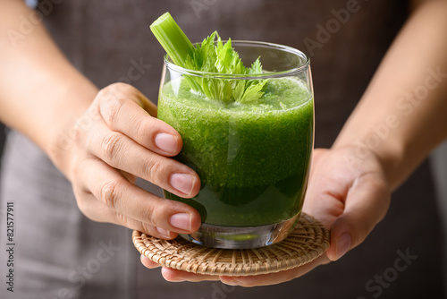 Celery green juice in glass holding by hand, Healthy drink for detox photo