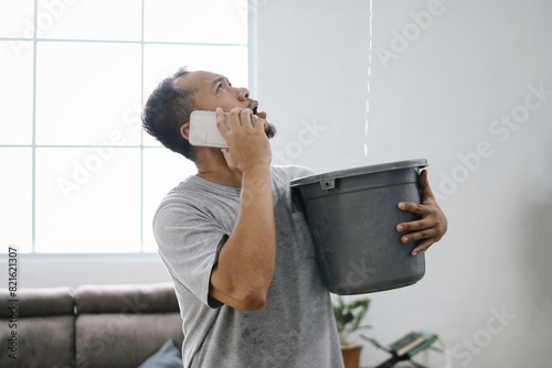 Water leaking from ceiling into buckets in living room as a man calling for insurance company 