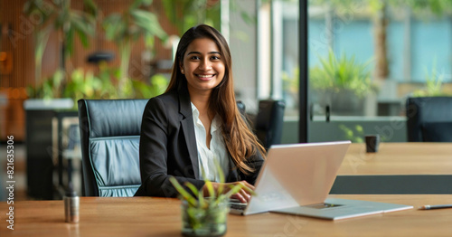 A young indian woman working on a laptop in office.