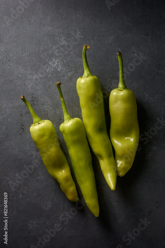 banana peppers on black textured background, long curved shape with mild heat and tangy sweet flavored popular chili pepper dark moody food photography with copy space