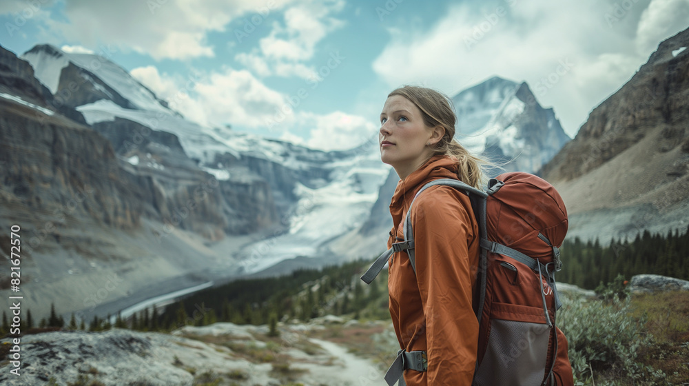 A focused young woman hiker explores majestic mountain scenery, her unwavering determination evident in her steady progress along the challenging trail