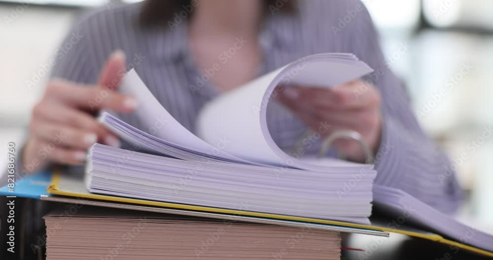 Woman quickly flips through stack of documents at workplace