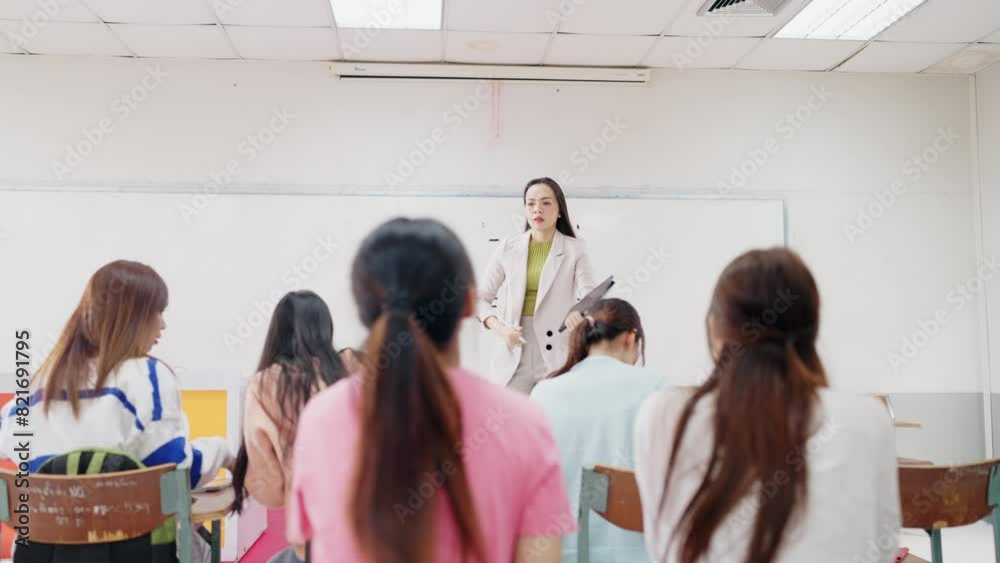 A teacher is standing in front of a group of students in a classroom ...