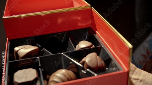 Female fingers pick chocolate candies from the box photo