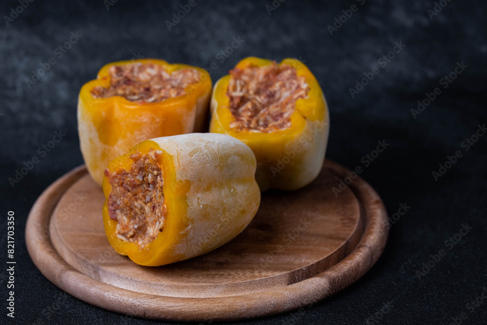 Frozen stuffed peppers filled with meat and rice, on dark black background, semi-finished, ready for cooking. Convenience and homemade frozen healthy meals. Frozen stuffed peppers filled with meat and rice, on dark black background, semi-finished, ready for cooking. Convenience and homemade frozen healthy meals.