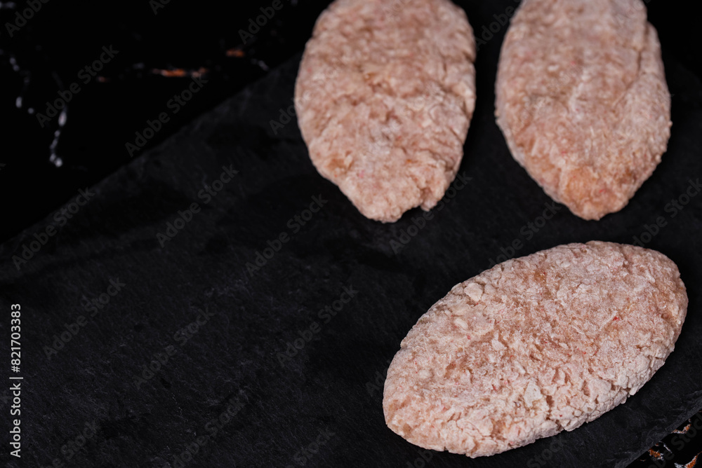 Frozen chicken meat cutlets on dark black background, semi-finished, ready for cooking. Convenience and homemade frozen healthy meals. Frozen chicken meat cutlets on dark black background, semi-finished, ready for cooking. Convenience and homemade frozen healthy meals.
