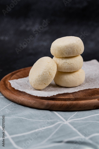 Frozen syrniki (cottage cheese pancakes) with vanilla flavor on dark black background, semi-finished, ready for cooking. Convenience and homemade frozen healthy meals.