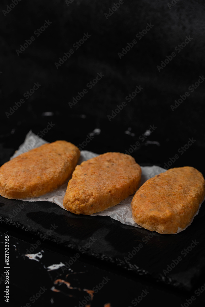 Frozen fish cutlets on dark black background, semi-finished, ready for cooking. Convenience and homemade frozen healthy meals. Frozen fish cutlets on dark black background, semi-finished, ready for cooking. Convenience and homemade frozen healthy meals.