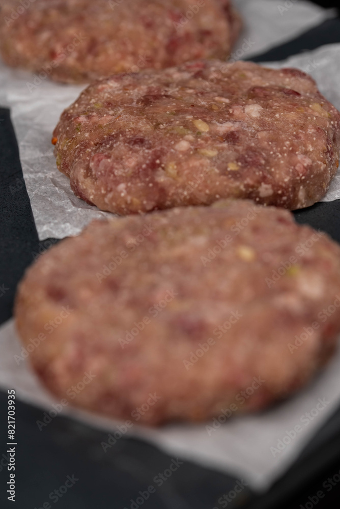 Frozen meat cutlets on dark black background, semi-finished, ready for cooking. Convenience and homemade frozen healthy meals.