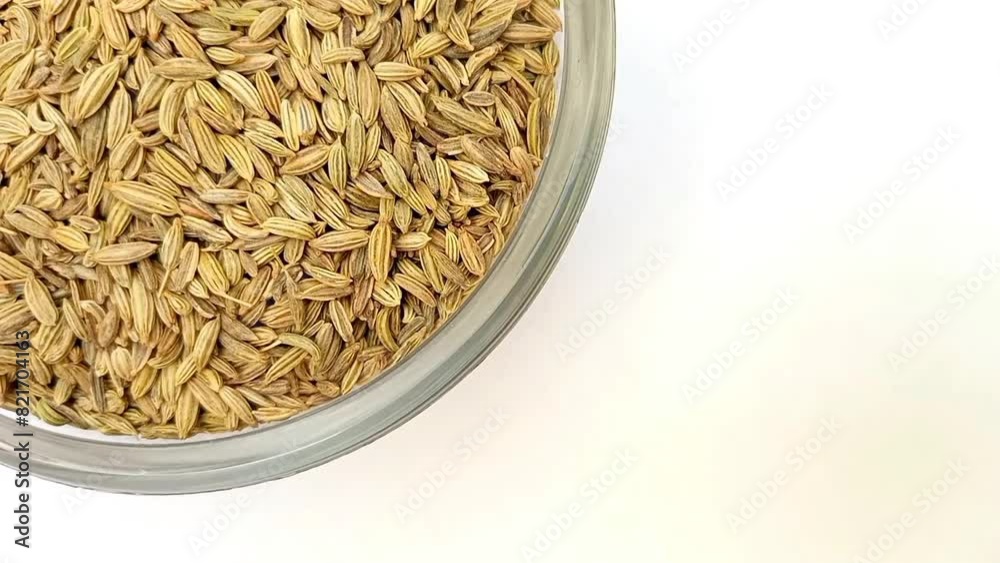 Fennel seeds in a glass bowl isolated rotating top left corner, a glass bowl full of Fennel seeds on white background, close up, herbs and spices.