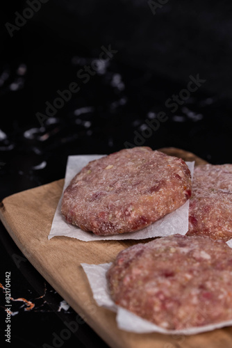 Frozen meat cutlets on dark black background, semi-finished, ready for cooking. Convenience and homemade frozen healthy meals.