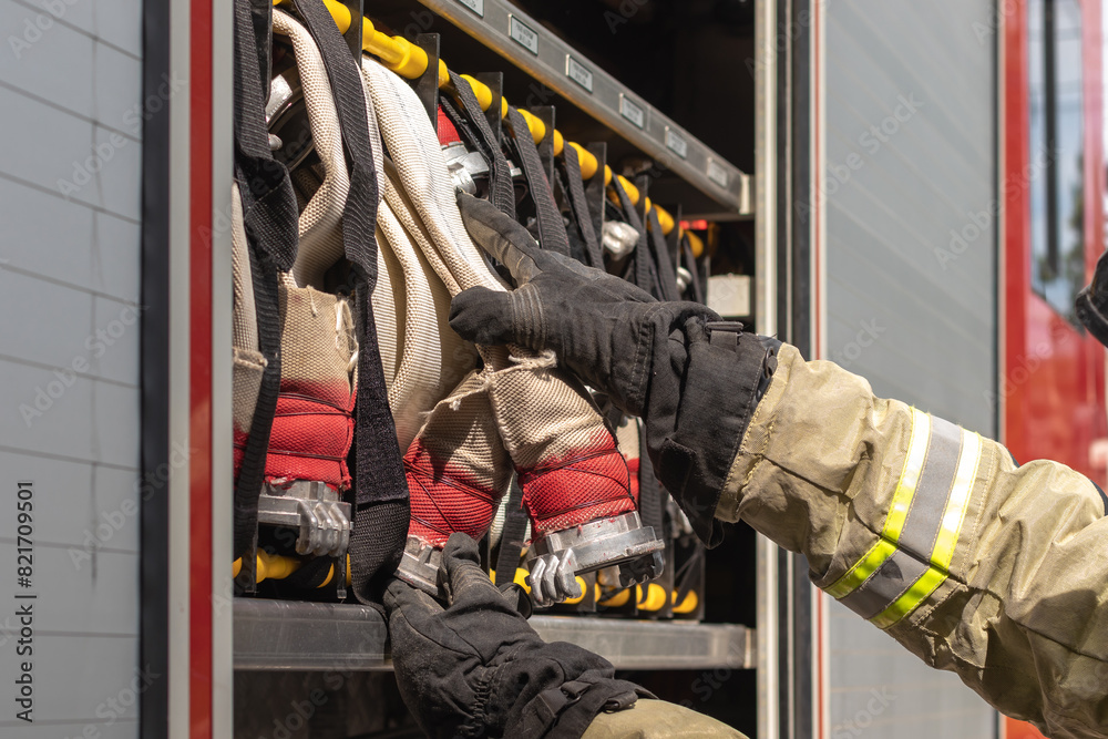 Fototapeta premium Firefighter removing water hose from fire truck