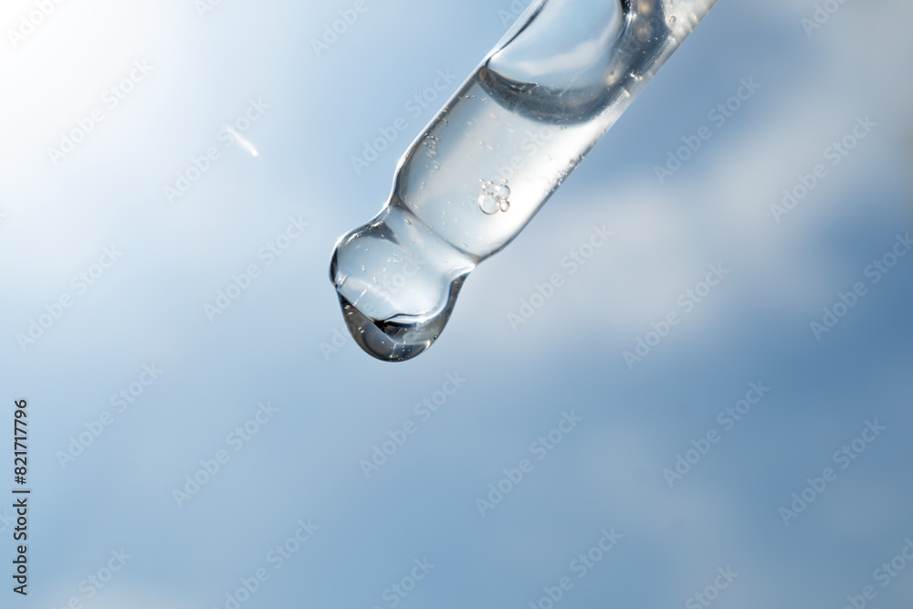 A drop of cosmetic aromatic oil drips from the pipette. Front view. A drop of cosmetic aromatic oil drips from the pipette. Front view.