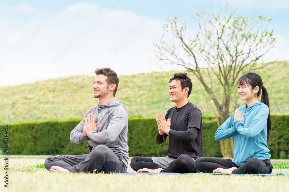 公園でヨガ・瞑想・マインドフルネスをするスポーツウェアの男女（プライベートレッスン）
