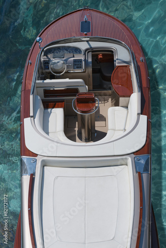 Luxurious large high-speed wooden boat on clear blue water top view. Expensive wooden boat on blue azure water, top view. Exclusive expensive boat on the clear azure water of the shore, top view.