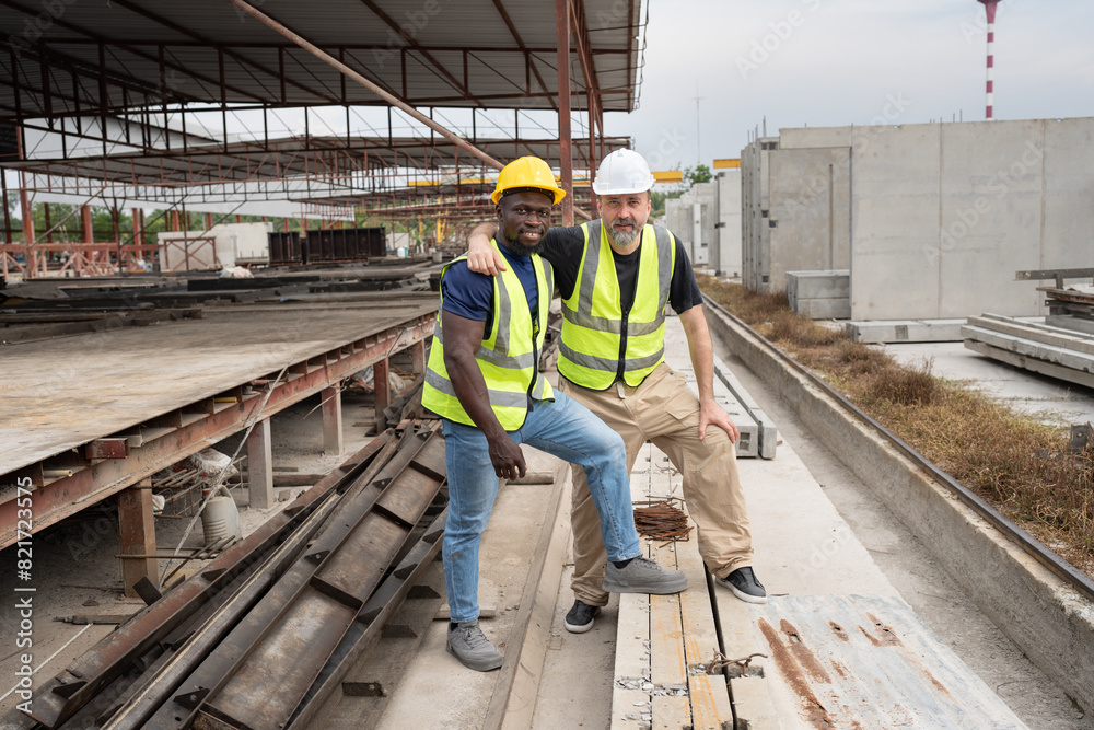Portrait happy caucasian engineer man hug with happy African American engineer man at precast cement outdoor factory Portrait happy caucasian engineer man hug with happy African American engineer man at precast cement outdoor factory