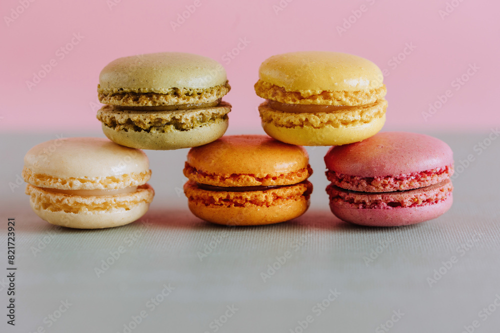Vibrant macarons stacked against a pastel background