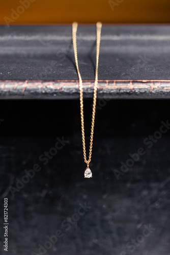 Gold necklace with a diamond pendant against a dark background photo
