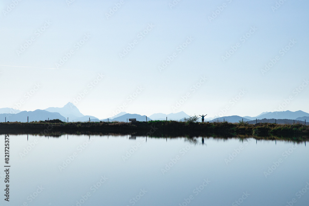 Peaceful lake scene with distant mountains and a lone figure