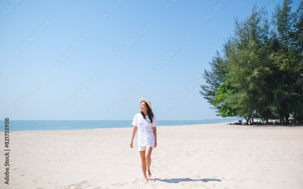 Portrait image of a young woman while strolling on the beach with the sea and blue sky background Portrait image of a young woman while strolling on the beach with the sea and blue sky background