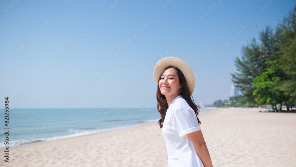 Portrait image of a young woman while strolling on the beach with the sea and blue sky background Portrait image of a young woman while strolling on the beach with the sea and blue sky background
