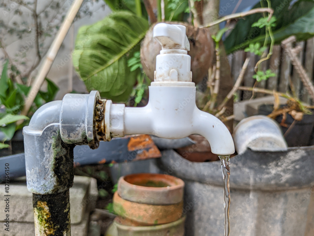 Plastic water tap with a leaking joint, where persistent drips have created the perfect environment for moss to thrive around the pipe. Plastic water tap with a leaking joint, where persistent drips have created the perfect environment for moss to thrive around the pipe.