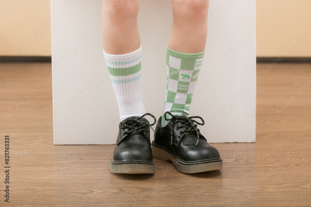 Kid wears different pair of socks. Child foots in mismatched socks, studio photography. Down syndrome awareness concept, odd socks day, anti-bullying week. Kid wears different pair of socks. Child foots in mismatched socks, studio photography. Down syndrome awareness concept, odd socks day, anti-bullying week.
