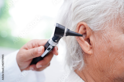 Otolaryngologist or ENT physician doctor examining senior patient ear with otoscope, hearing loss problem.