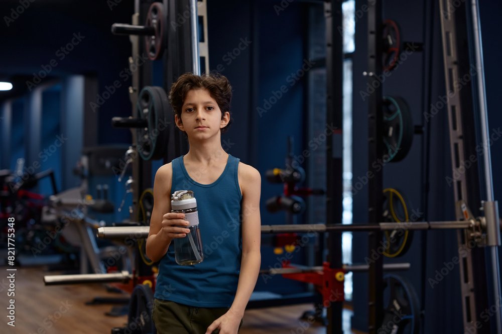 Tired preteen boy having rest after training session at gym Tired preteen boy having rest after training session at gym