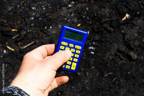 Blue calculator in dark soil, burnt ground after the fire