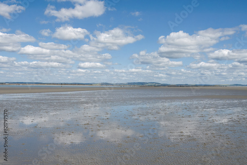 clouds and blue sky reflecting in the water on the beach at West Wittering West Sussex England