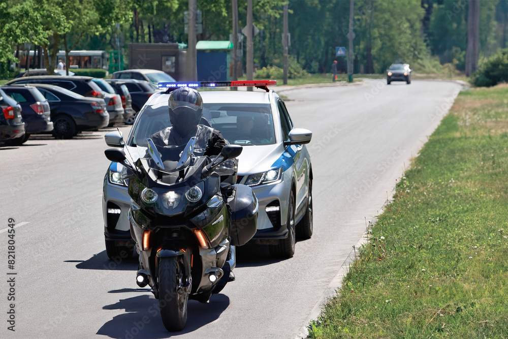 A police officer confidently rides a motorcycle down a bustling street, blending in seamlessly with the flow of traffic, keeping a watchful eye on their surroundings A police officer confidently rides a motorcycle down a bustling street, blending in seamlessly with the flow of traffic, keeping a watchful eye on their surroundings