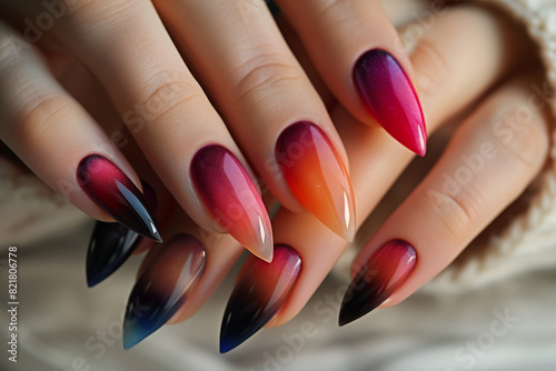 close up manicure with ombre nail art, long pointy nails in pink, red, orange, purple tones © Ricky