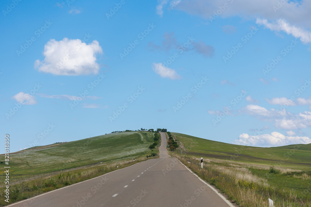 Road in green hills in sunny day. Georgia. Beautiful mountain roadway, green grass, blue sky, white clouds. Landscape Road in green hills in sunny day. Georgia. Beautiful mountain roadway, green grass, blue sky, white clouds. Landscape